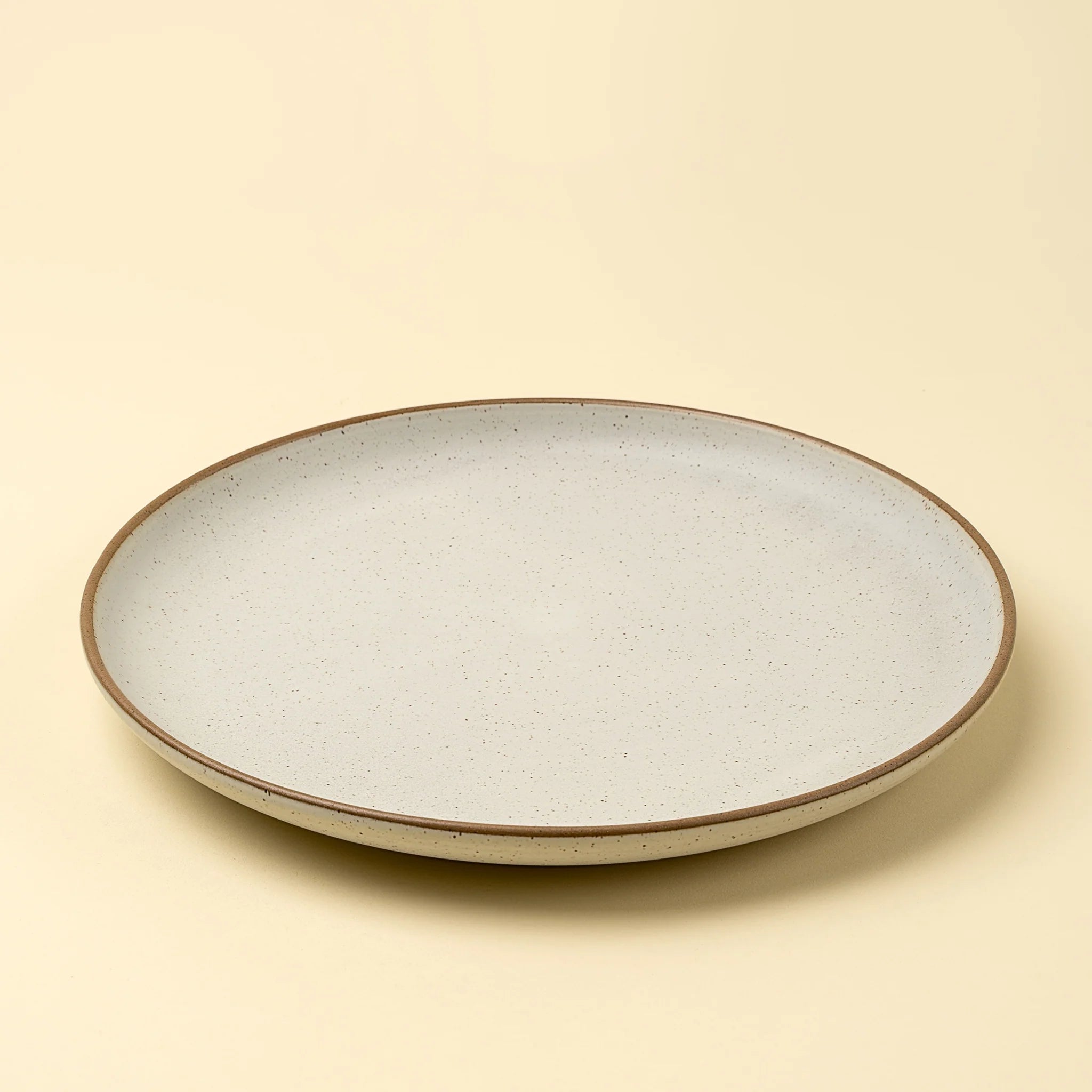 Round ceramic plate with a speckled design on a beige background